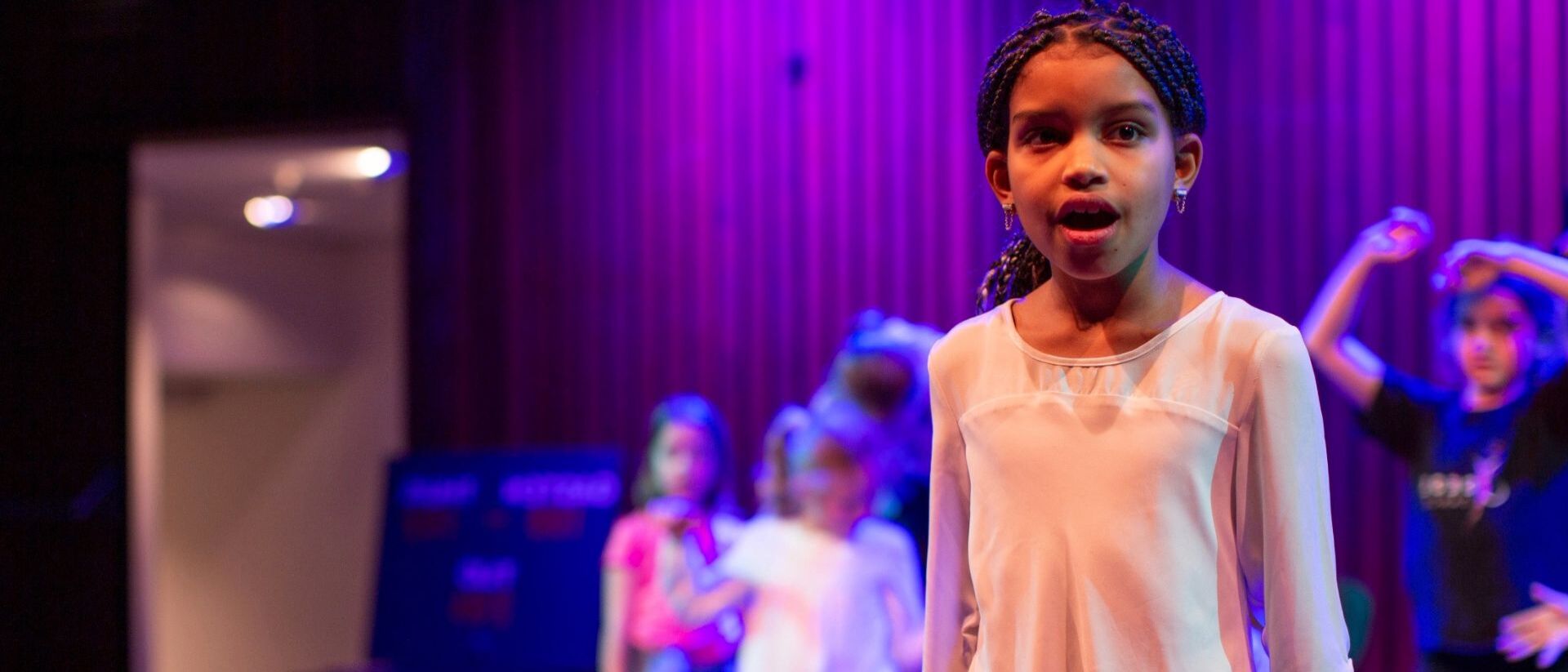 Een kindje zingt op een podium.