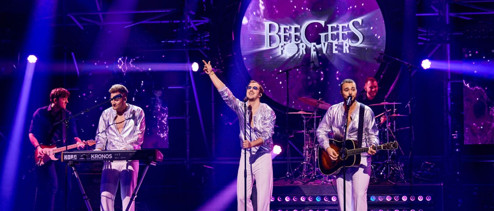 Band Bee Gees Forever geeft een optreden op een podium met paarse lichten