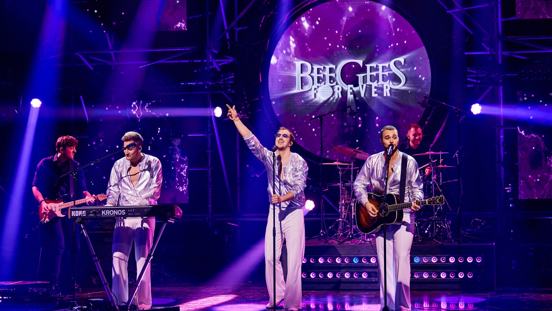 Band Bee Gees Forever geeft een optreden op een podium met paarse lichten