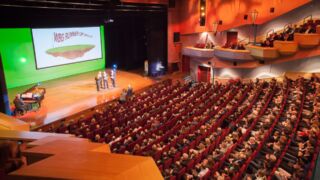 Volle zaal met mensen die naar een presentatie kijken