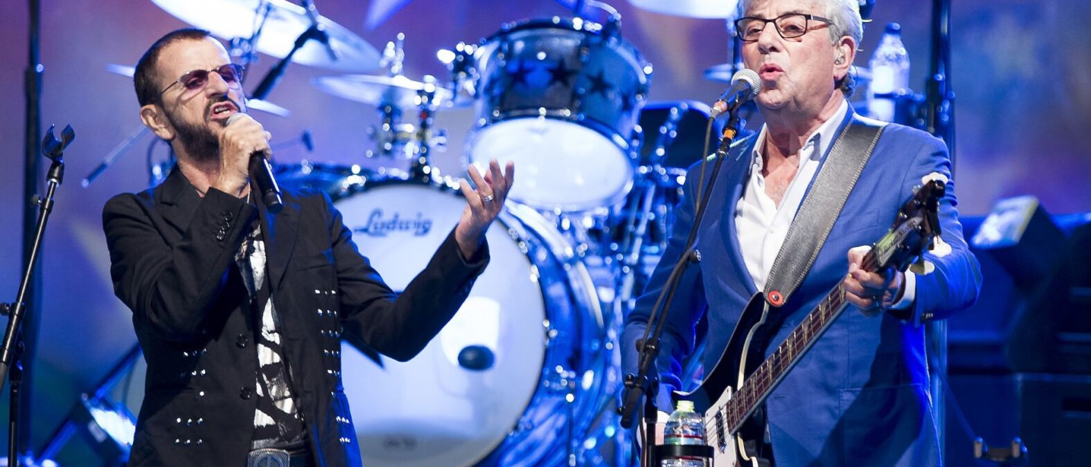 Twee mannen zingend op het podium met achter hen een drumstel