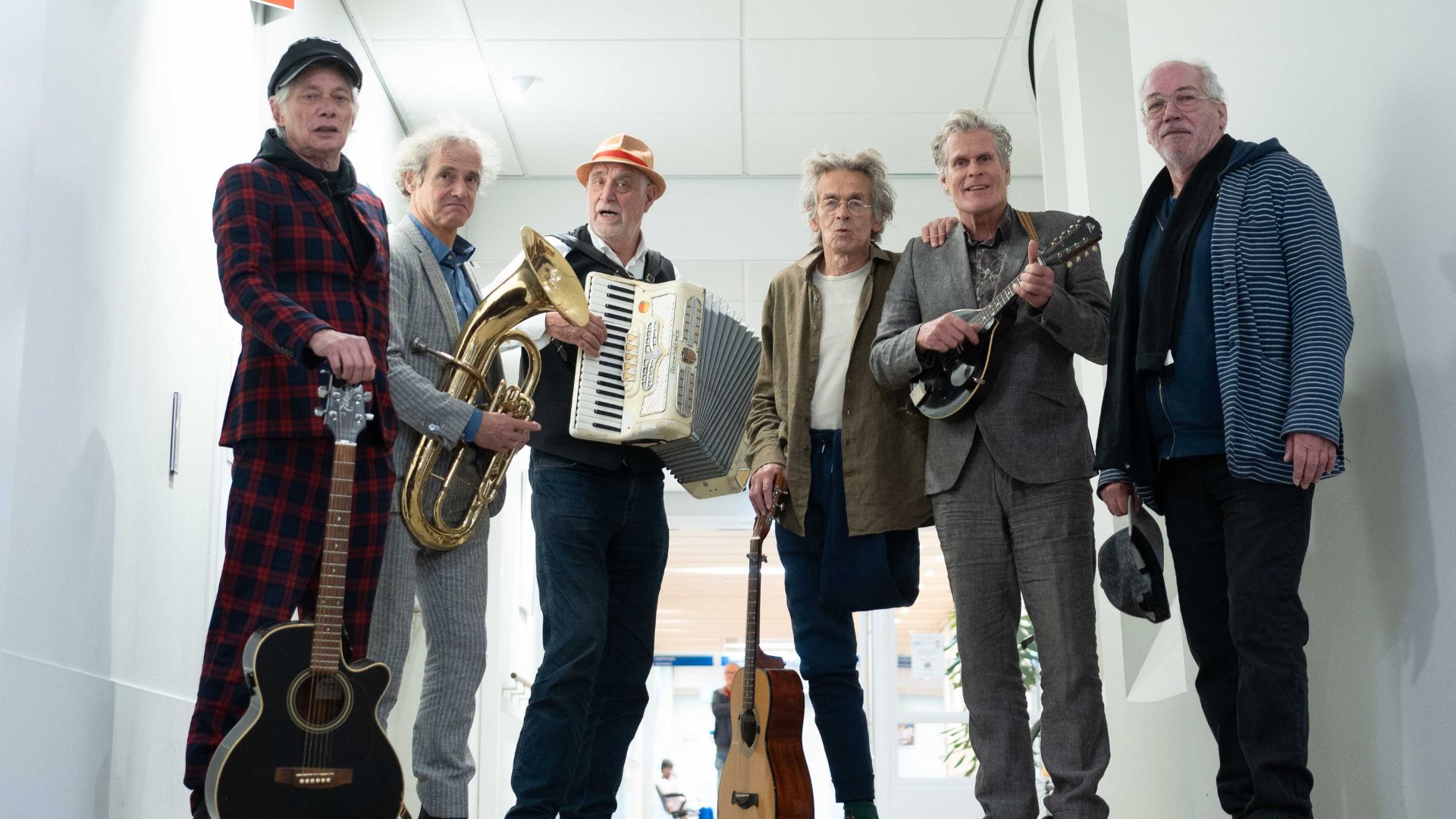 De heren van De Navertellers staan op een rij, ieder met een instrument in handen.