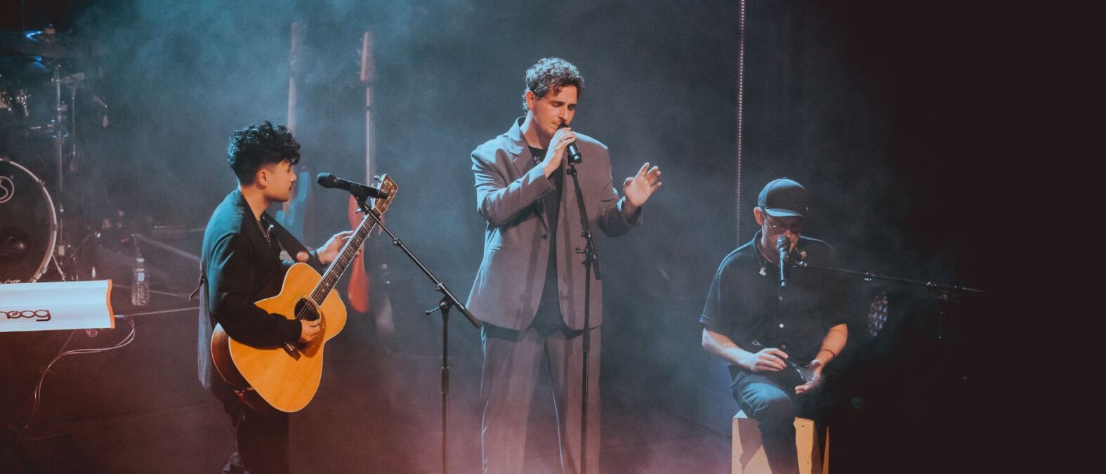 Nielson en zijn band, optredend op het podium. Om hen heen theaterlicht en rook.