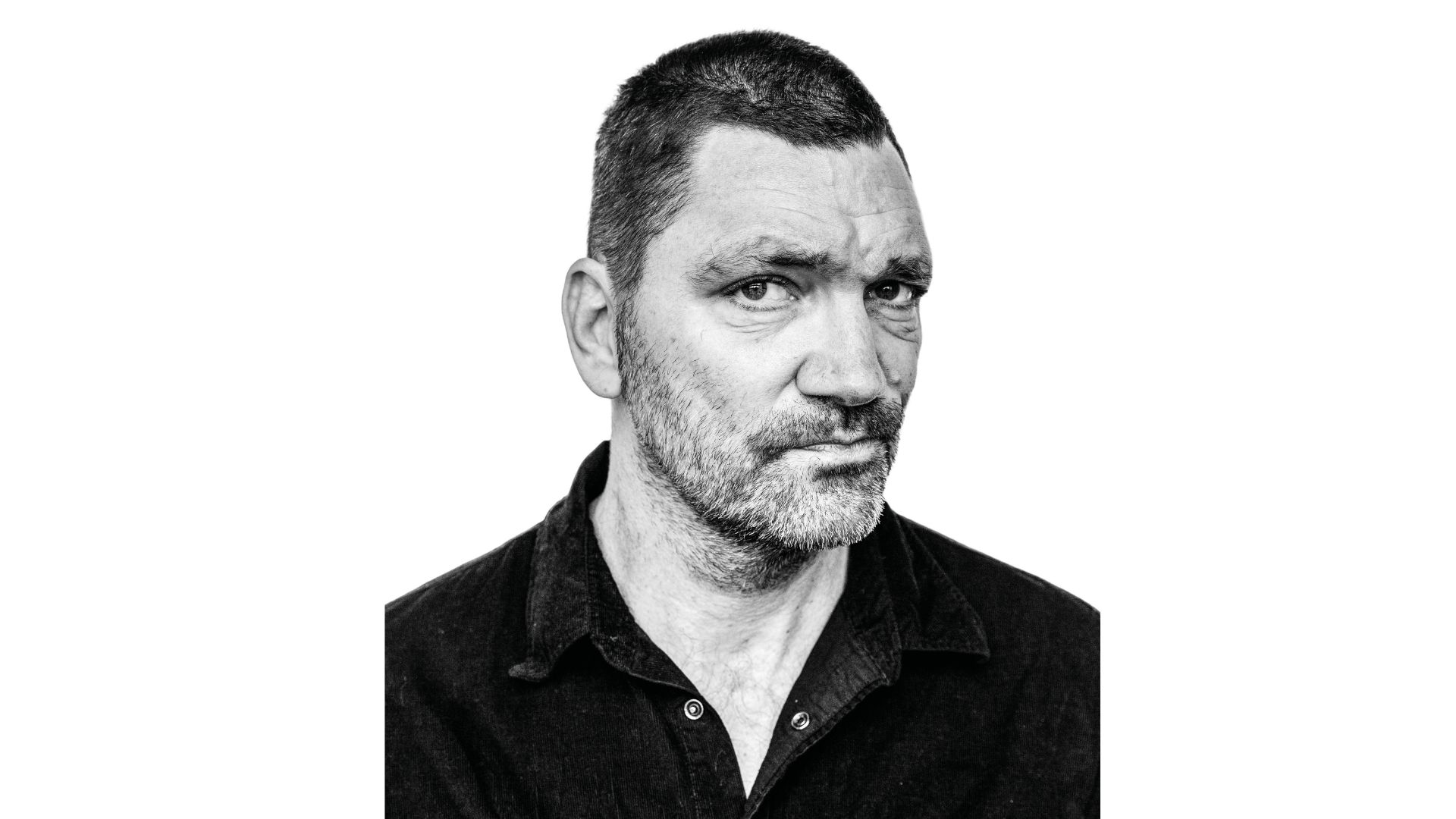 op de foto zie je theo maassen in het zwart wit die bedenkend kijkt