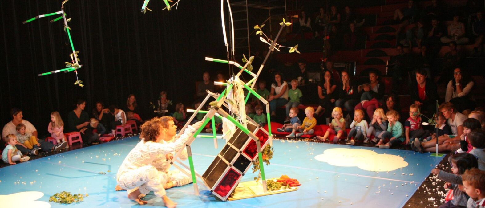 Kinderen zitten om een vlakke vloer toneel met groots gebouwd bouwwerk.