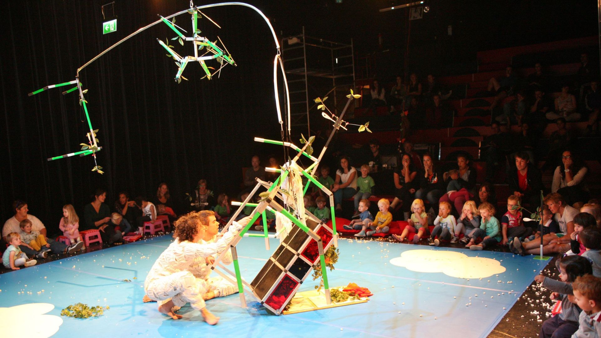 Kinderen zitten om een vlakke vloer toneel met groots gebouwd bouwwerk.