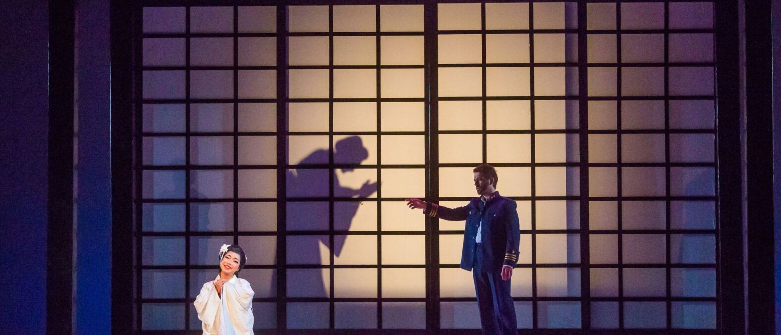 Scènefoto van Madame Butterfly keizerin knielt in wit gewaad.