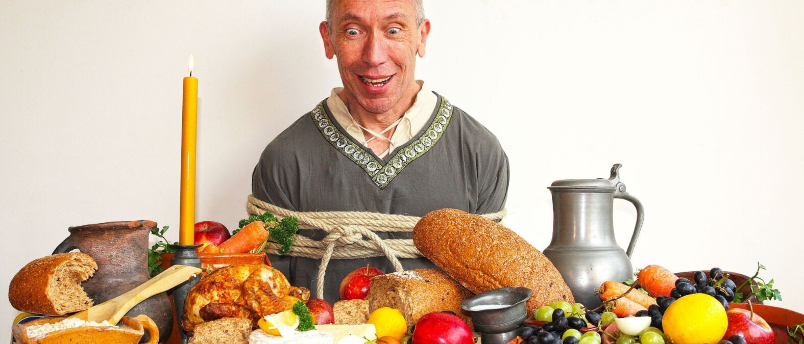 Lunch voorstelling, man met gele kaars met allerlei eten op tafel.