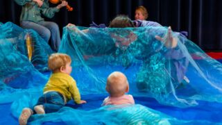 Doorschijnend blauw doek en twee kruipende baby's.