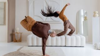 Een danser balanceert op een arm en een andere danser schudt met haar haren