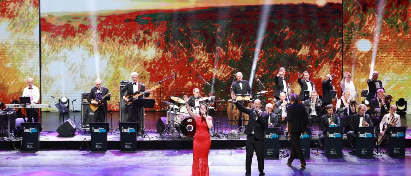 Bigband MissJones treedt op op een groot podium. Een man en een vrouw zingen samen