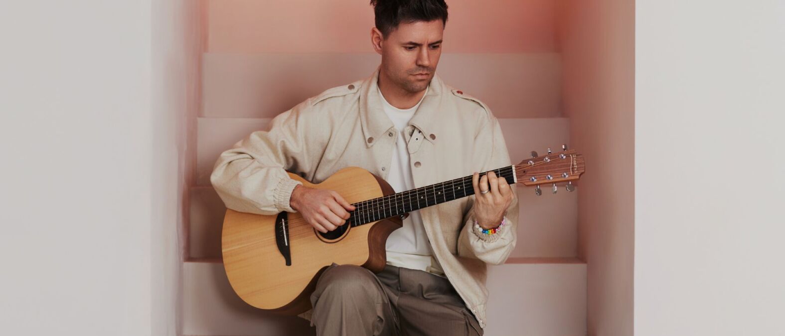 Simon Keizer, zittend op een trap met een gitaar in zijn handen.