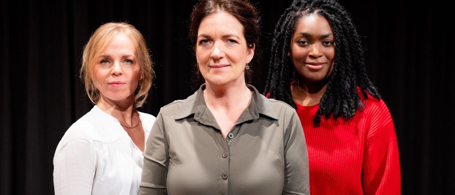 Drie vrouwen staan naast elkaar en glimlachen naar de camera