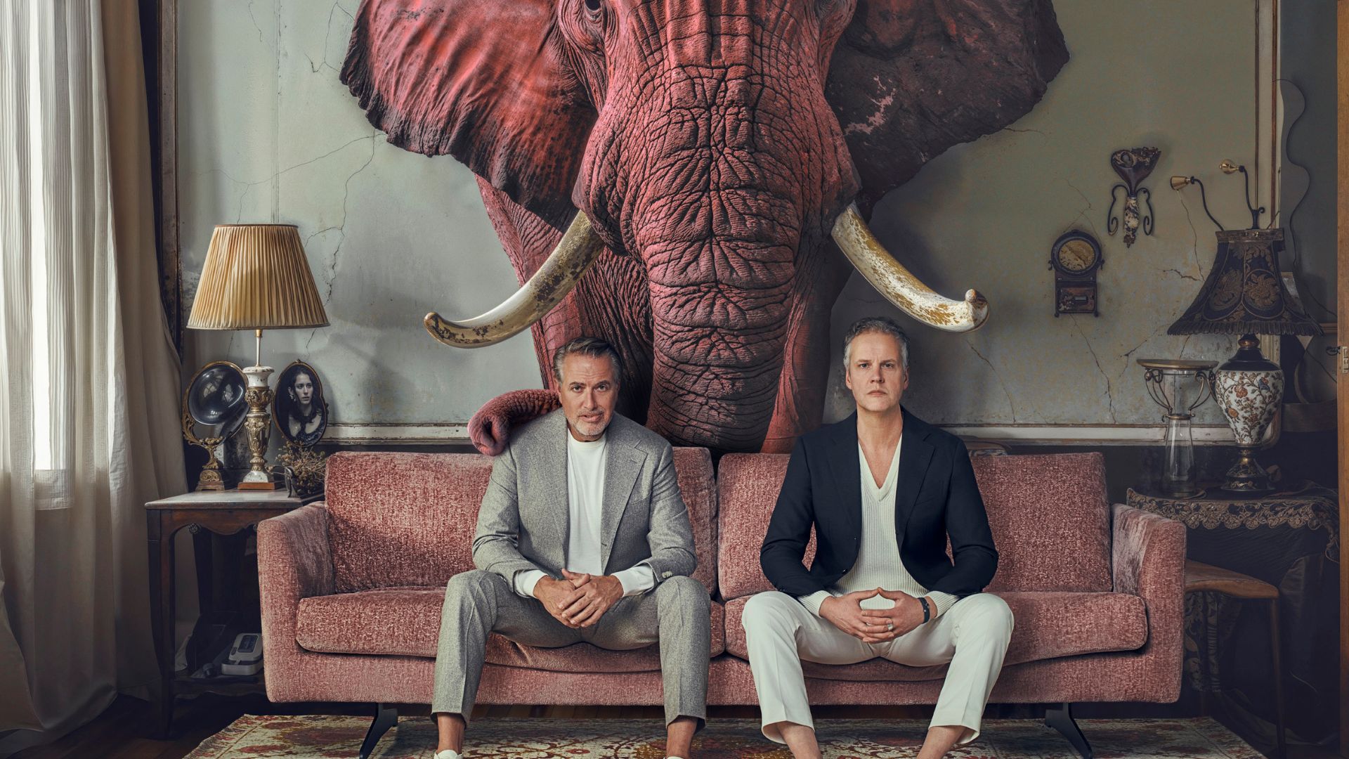 Veldhuis & Kemper op een rode bank met een rode olifant achter hun