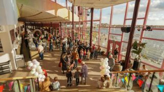 Overzichtsfoto van de foyer met bezoekers en ballonnenbogen