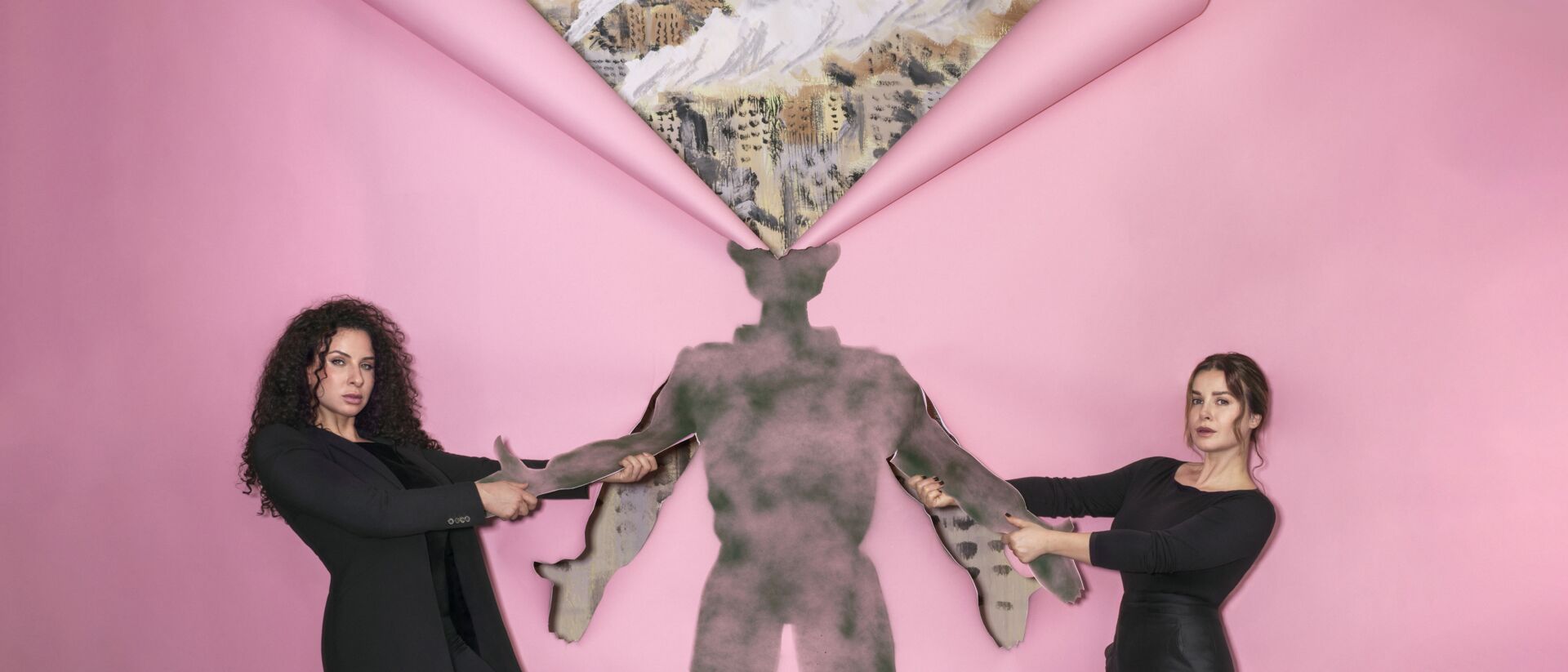 Twee vrouwen in zwart trekken aan de armen van een silhouet van een manfiguur, met een roze achtergrond waaruit boven zijn hoofd een driehoekige opening zichtbaar is met een schilderachtig landschap.
