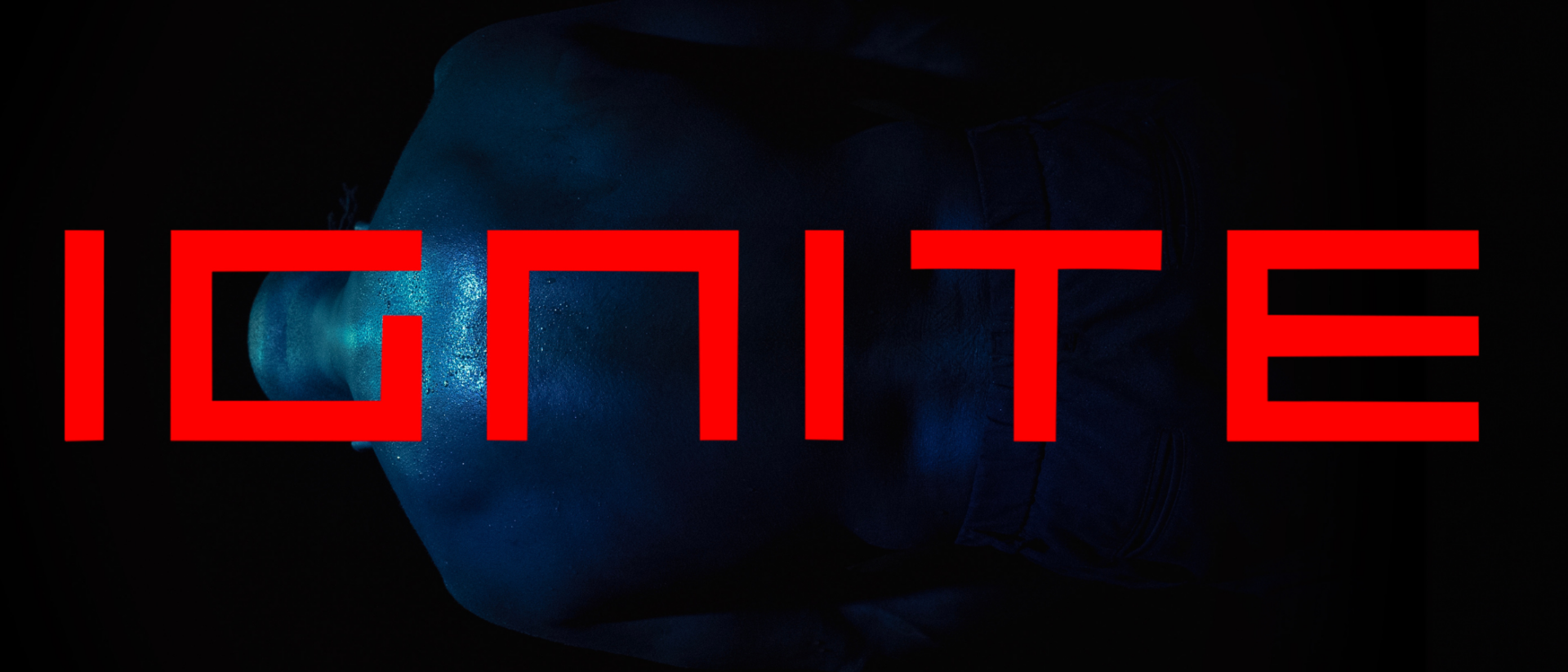 Donker verlichte afbeelding van een blote, bezwete rug in blauw licht, met het woord “IGNITE” felrood en in hoofdletters over het beeld geplaatst.