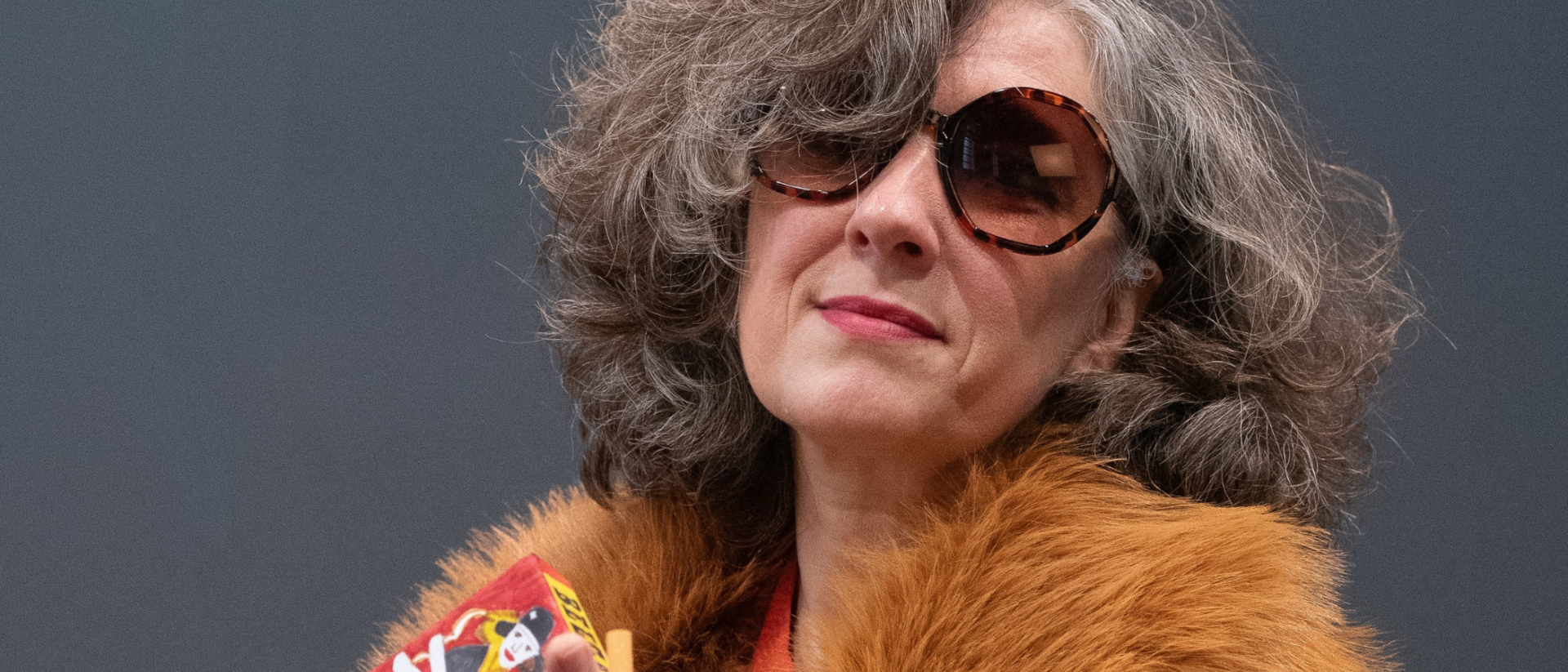 Een vrouw kijkt de camera in met een pakje sigaretten.