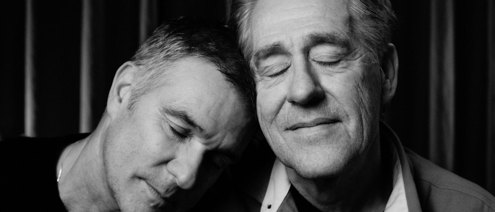 Peter en Viggo, de een leunt met zijn hoofd op de schouder van de ander. Beide hebben hun ogen dicht.