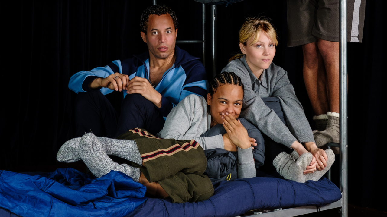 Drie personen op een stapelbed met verschillende gezichtsuitdrukkingen