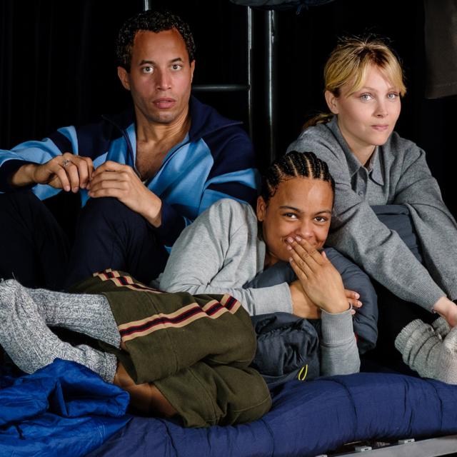 Drie personen op een stapelbed met verschillende gezichtsuitdrukkingen