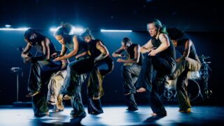Zeven dansers in krachtige choreografie op verlicht podium - Dansers tijdens voorstelling Closed Eyes