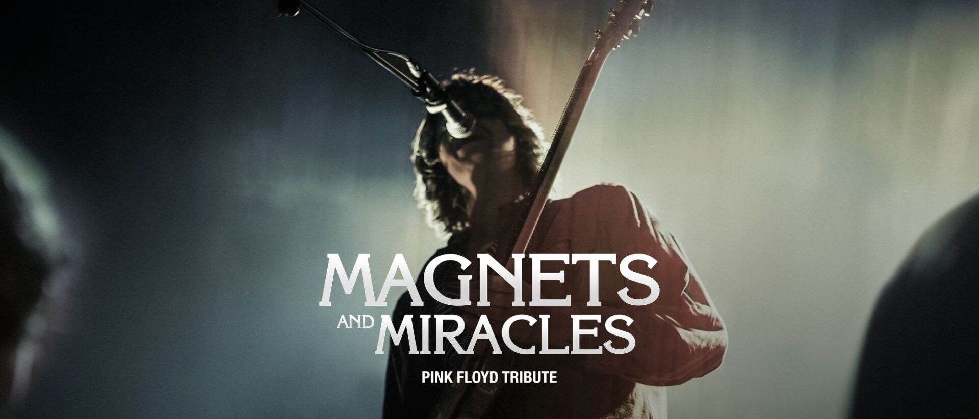 Livebeeld van Magnets and Miracles met zanger-gitarist in spotlicht.