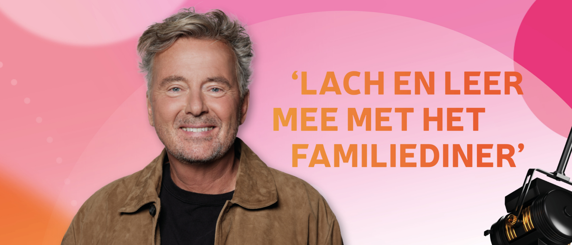 Man met grijs haar en beige jas staat lachend voor een kleurrijke achtergrond met de tekst: