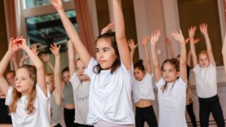 Kinderen die ballet doen met handen in de lucht