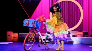 Tineke schouten op het podium met een fiets en een pruik op