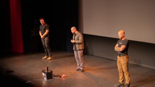 De drie heren van schokbestendig staan op het podium