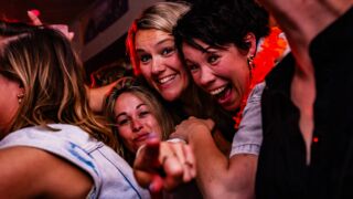 Foto van feestende vrouwen die in de camera kijken