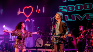 Twee zangers op verlicht podium tijdens Top 2000 Live Listen to the Music Hoorn