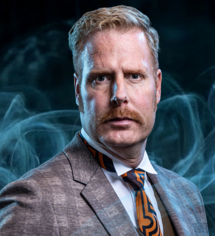 Ferdi Stofmeel als Dr. John Watson in grijs pak met hoed in musical Sherlock Holmes