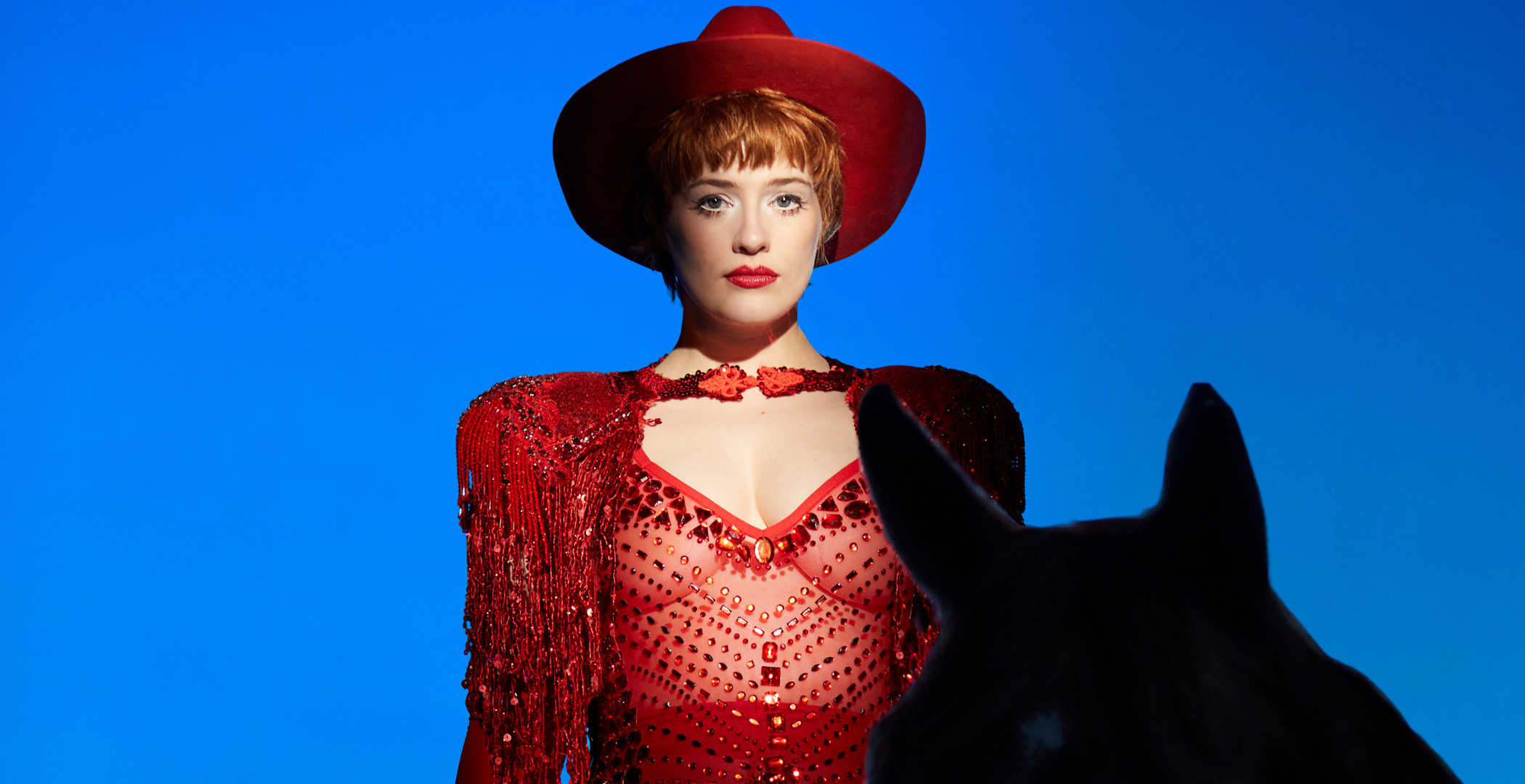 Valentina Tóth in rood glitterkostuum met zwart paard voor Revue Revanche Hoorn