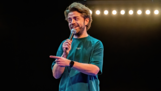 Daan van der Hoeven met microfoon op podium tijdens cabaretvoorstelling Mensenmens