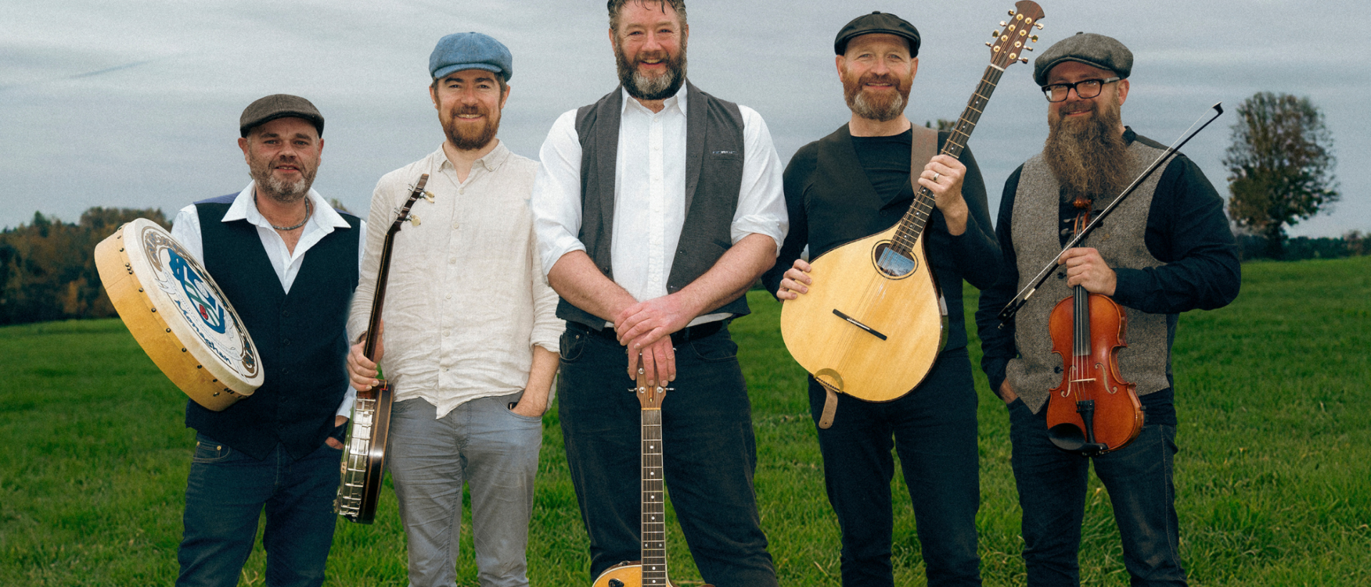Vijf muzikanten van The Dubliners Experience met Ierse instrumenten in groene weide Hoorn