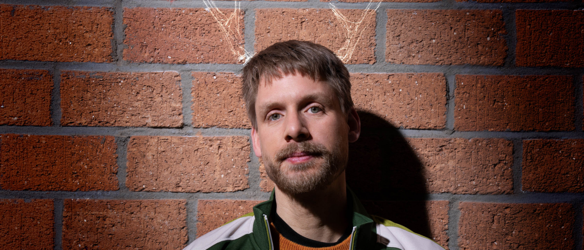 Thijs van de Meeberg als Baby Reindeer met gekritte geweien op bakstenen muur