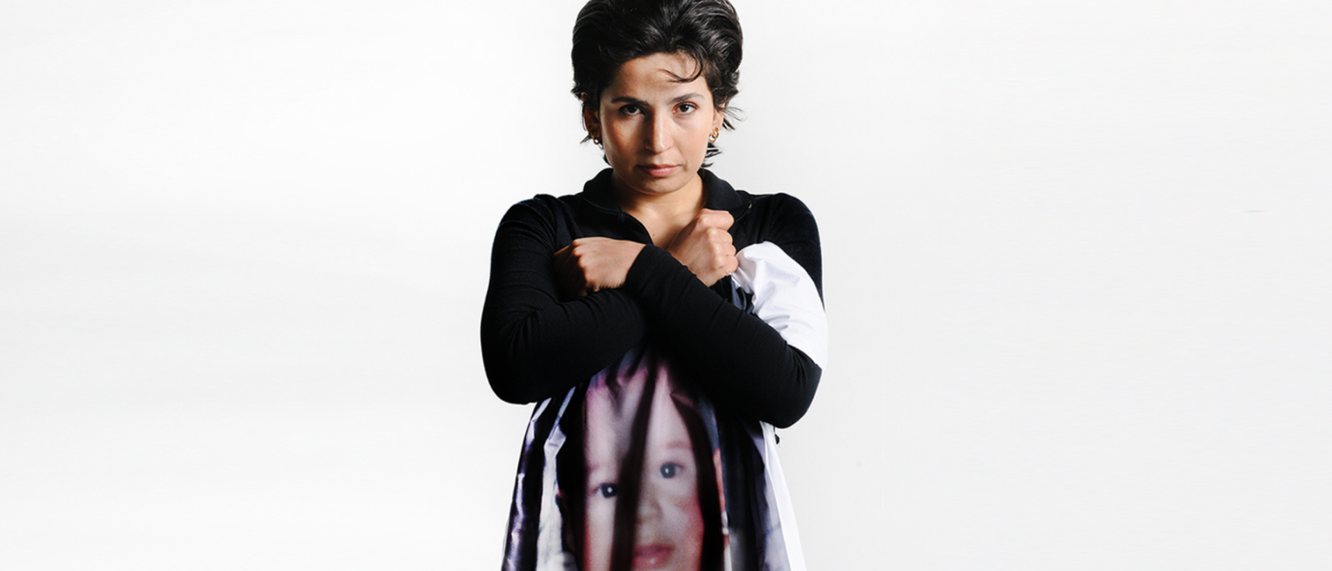 Sinem Kavus in vechthouding met kinderfoto op jurk, campagnebeeld Bijna een leven Toneelgroep Maastricht