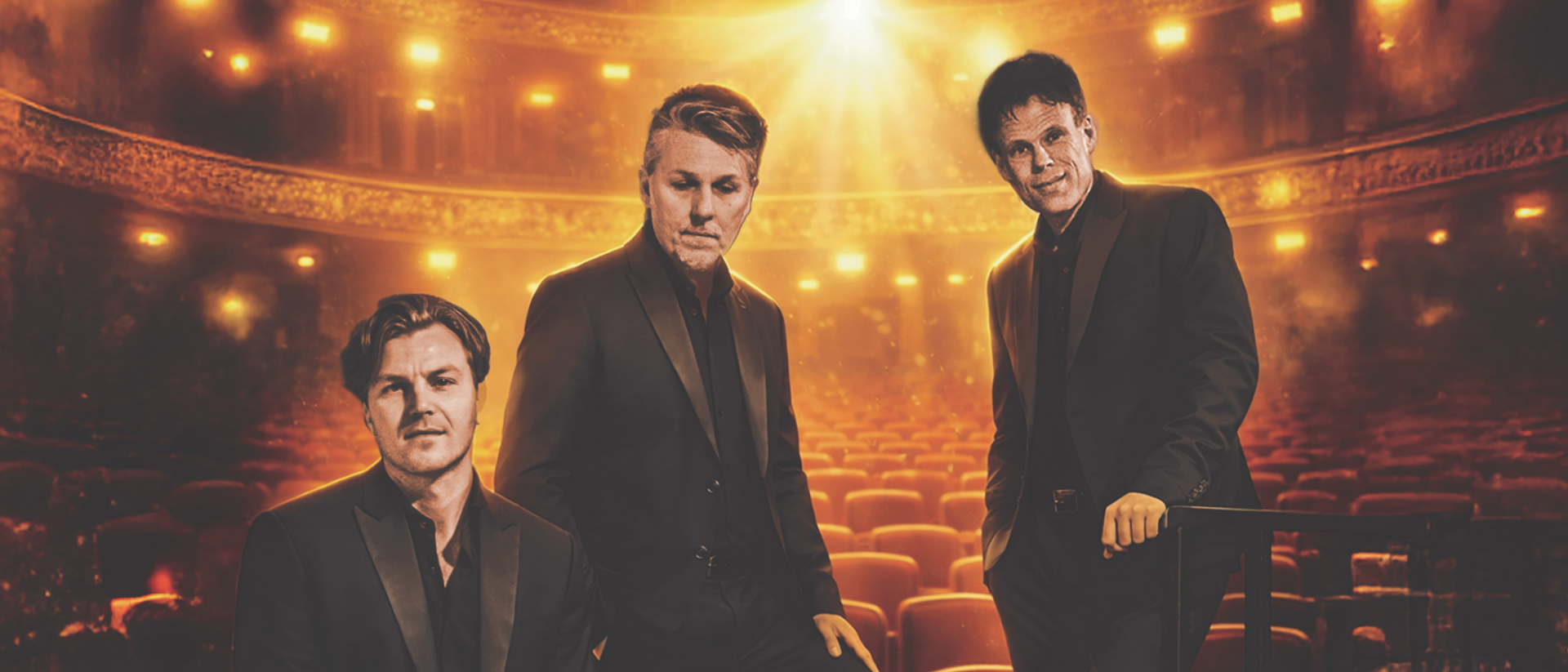 De drie leden van 3JS in zwarte pakken in een gouden theaterzaal voor 20 jaar 3JS
