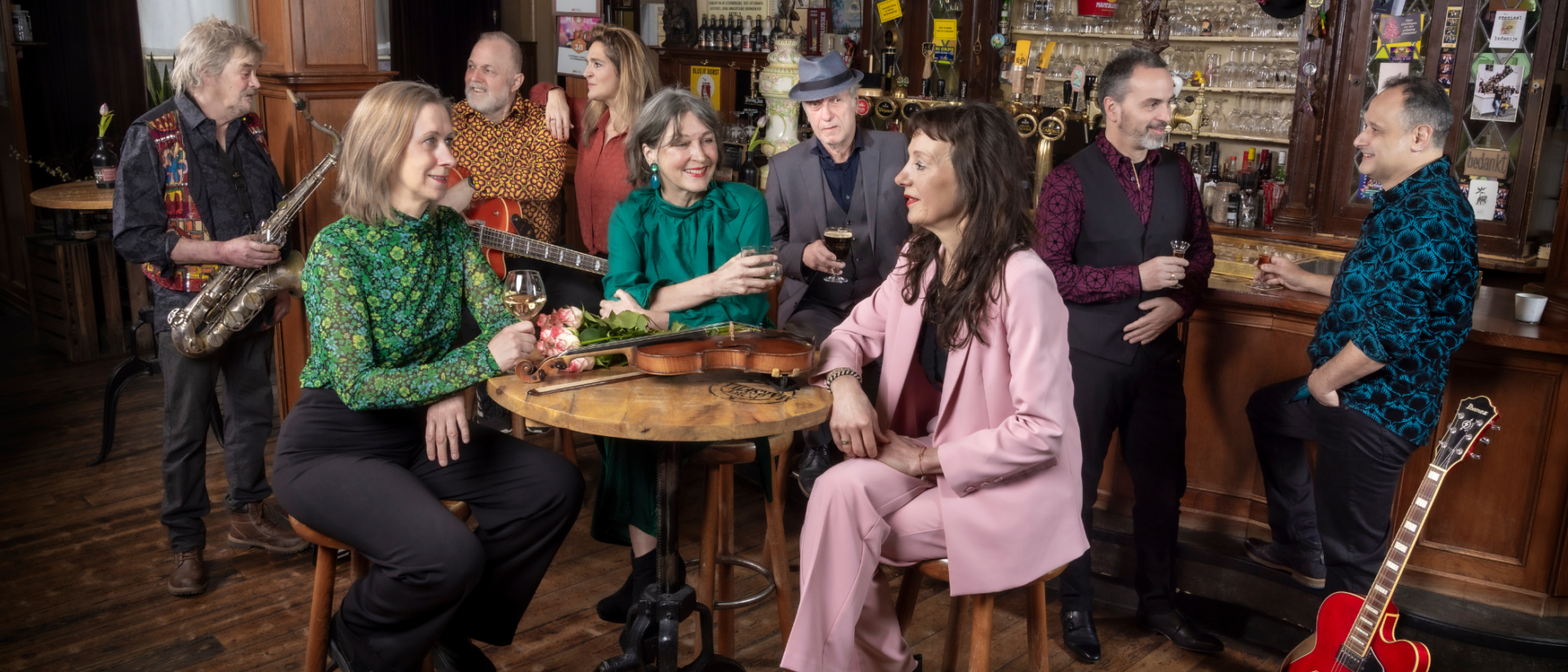 Negen muzikanten van Tonight Will Be Fine in een bruine kroeg met saxofoon, viool en gitaar