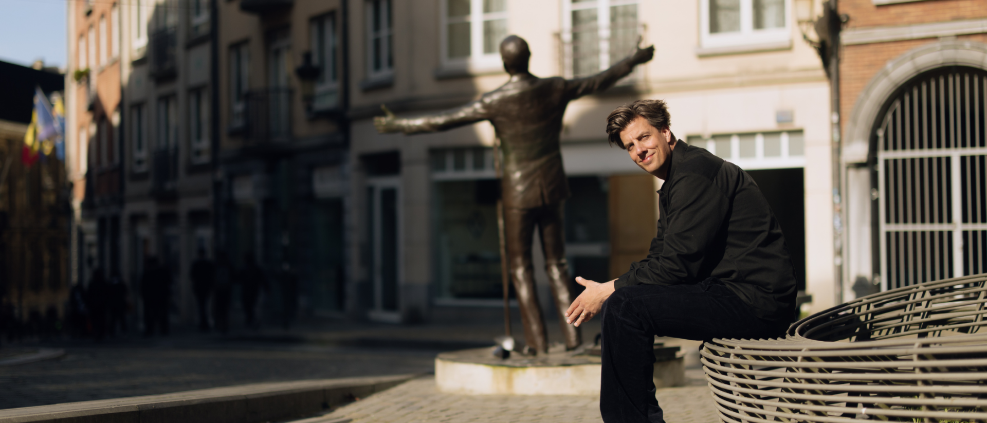 Rob Kemps zittend op bankje voor bronzen standbeeld stadsplein Laat me niet alleen